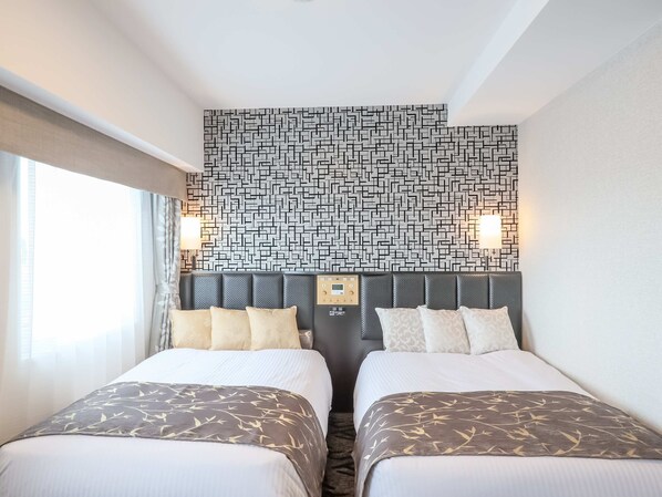 A hotel room with two beds, a patterned wall, and a control panel on the headboard.