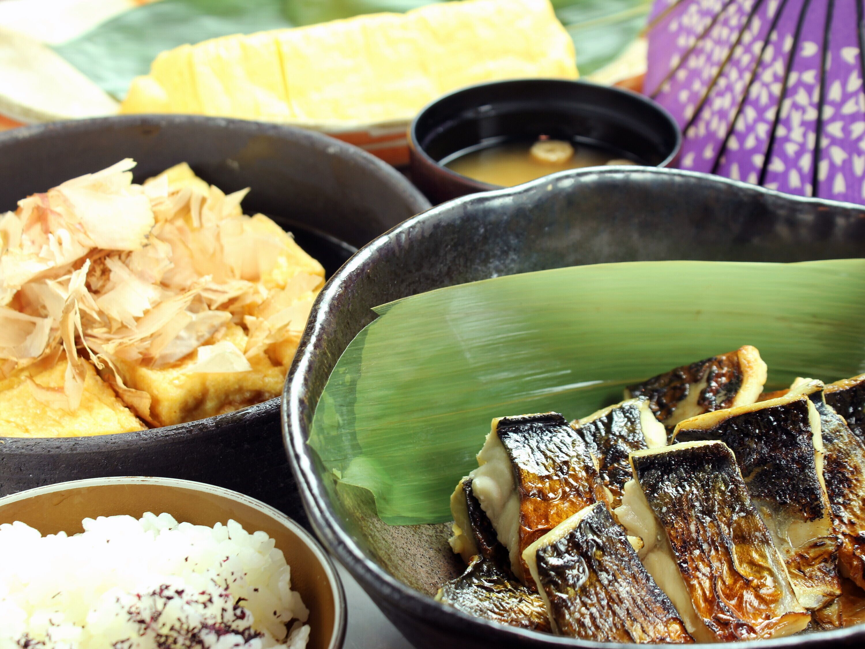 Diversos platos, incluyendo pescado a la parrilla, arroz y un tazón de sopa de miso.