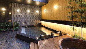 Un moderno espacio de spa con jacuzzi, suelo de madera y plantas de bambú.