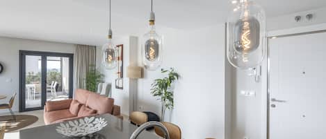 Una cocina moderna con una isla central, luces colgantes y un comedor con sillas.