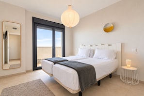 A bedroom with a bed, a bedside lamp, a mirror, and a view through a door.
