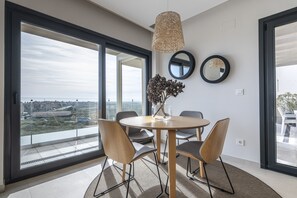 Un espace repas moderne avec une table ronde, quatre chaises et un luminaire suspendu.