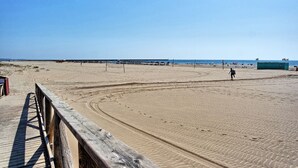 Une plage de sable avec une promenade en bois qui mène à l’eau.