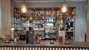 A bar area with shelves of liquor bottles, glasses, and a coffee machine. - DORMERO Hotel Bremen (Bremen)