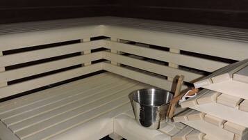 A sauna with a wooden bench, a metal bucket, and a wooden tool.
