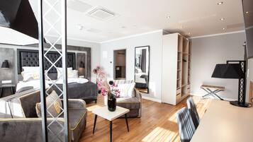 Una habitación de hotel moderna con una cama grande, una zona de estar con una mesita de café, un espejo y un armario.