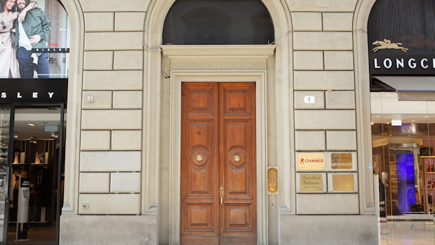 A double wooden door with a plaque, a storefront with a sign, and a partial view of a building facade. - Florence Luxury Apartment al Duomo by Mmega (Florence)