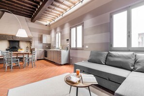 A modern kitchen with a dining area, a sofa, and a coffee table with books and a cup.