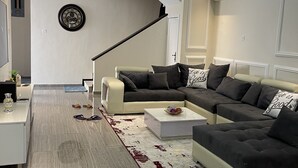 Ein modernes Wohnzimmer mit einem Ecksofa, einem Couchtisch und einer großen Uhr an der Wand.