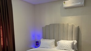 Ein modernes Schlafzimmer mit einem großen Bett, einer Klimaanlage und einem Nachttisch mit einer Lampe.