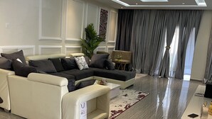 Ein modernes Wohnzimmer mit einem Ecksofa, einem kleinen Beistelltisch und einem Blumentopf.
