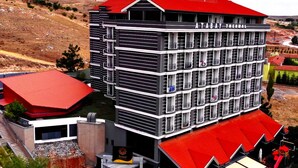 A multi-story hotel with a red roof, balconies, and a sign reading "AT BAY THERMAL". - Atabay Termal Hotel (Kozakli)