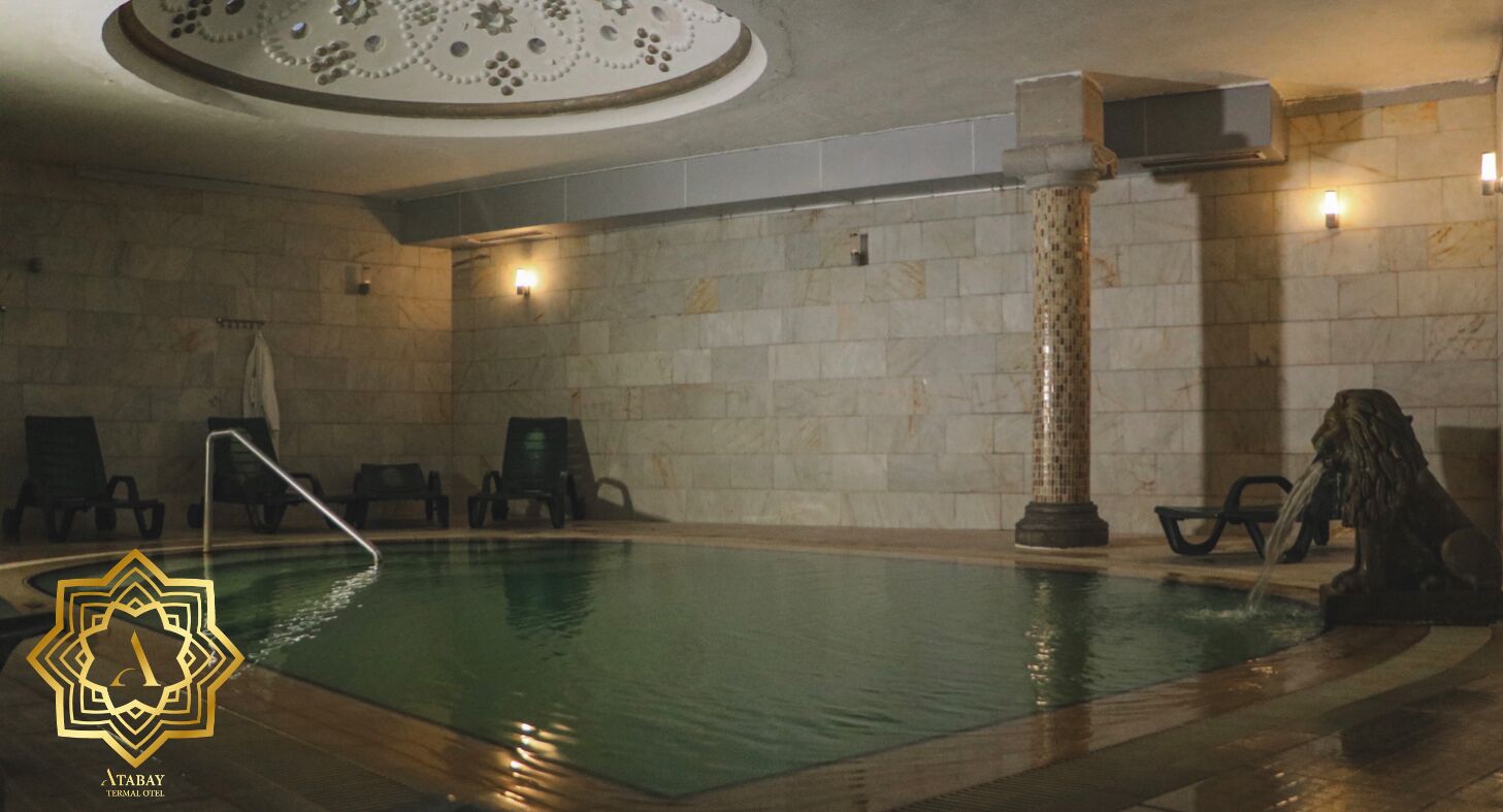 Une piscine avec des chaises longues et une colonne décorative.