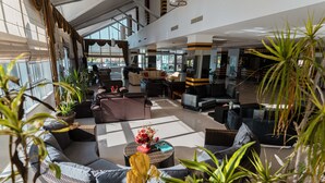 A spacious indoor area with seating arrangements, potted plants, and a reception desk. - Atabay Termal Hotel (Kozakli)