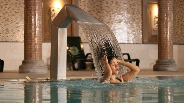 A person in a pool with a water feature overhead. - Atabay Termal Hotel (Kozakli)