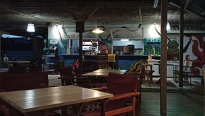 A restaurant with wooden tables and chairs, a counter with a menu, and a mural on the wall. - Bluetel Lixouri, Greece (Kefalonia)