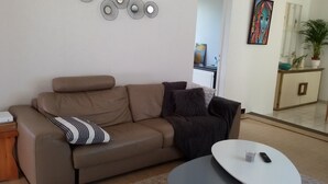 A living room with a beige sofa, a coffee table, and a painting on the wall.