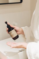 Una persona sosteniendo una botella de loción corporal Meraki en un baño.