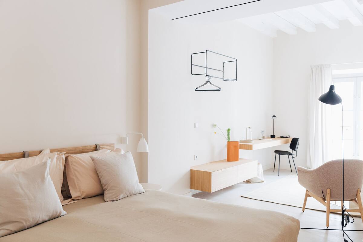 A modern bedroom with a bed, bedside table, and a desk area with a chair.