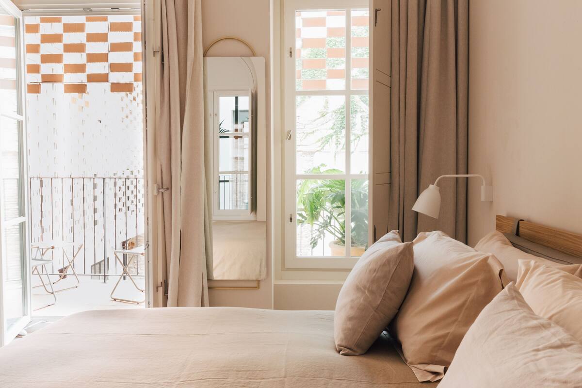 A bedroom with a bed, a window, and a view of the outside.