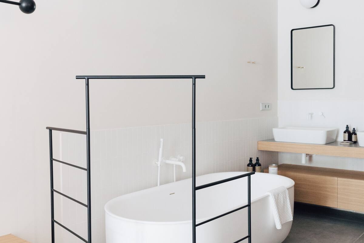 A modern bathroom with a freestanding bathtub, a wooden vanity, and a large mirror above the sink.