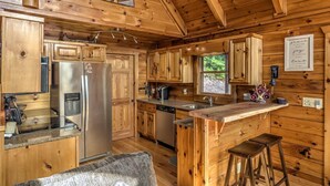 Ein Holzblockhaus-Interieur mit einer Küche, die eine zentrale Kochinsel, Edelstahlgeräte und Holzschränke bietet.