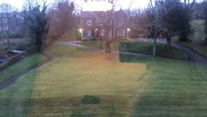 A view of a grassy area with a stone building in the background. - Captivating 2-bed Apartment in Isle of Bute (Rothesay)