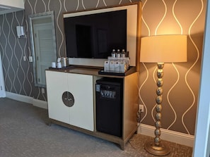 Um minibar compacto com televisão, máquina de café e pequeno frigorífico.