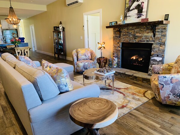A living room with a sofa, armchairs, a coffee table, and a fireplace.
