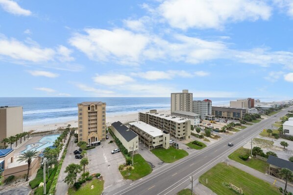 A coastal hotel with multiple buildings, a swimming pool, and a beach view.