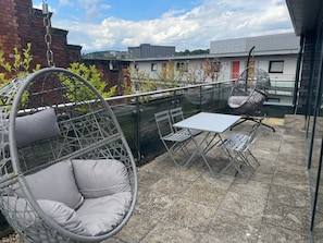 A patio with a hanging chair, a table, and chairs.
