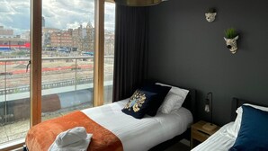 A hotel room with a large window, a bed with an orange throw, a black headboard, and a wall-mounted zebra head decoration. - Stay Angels Blonk Street Apartments (Sheffield)