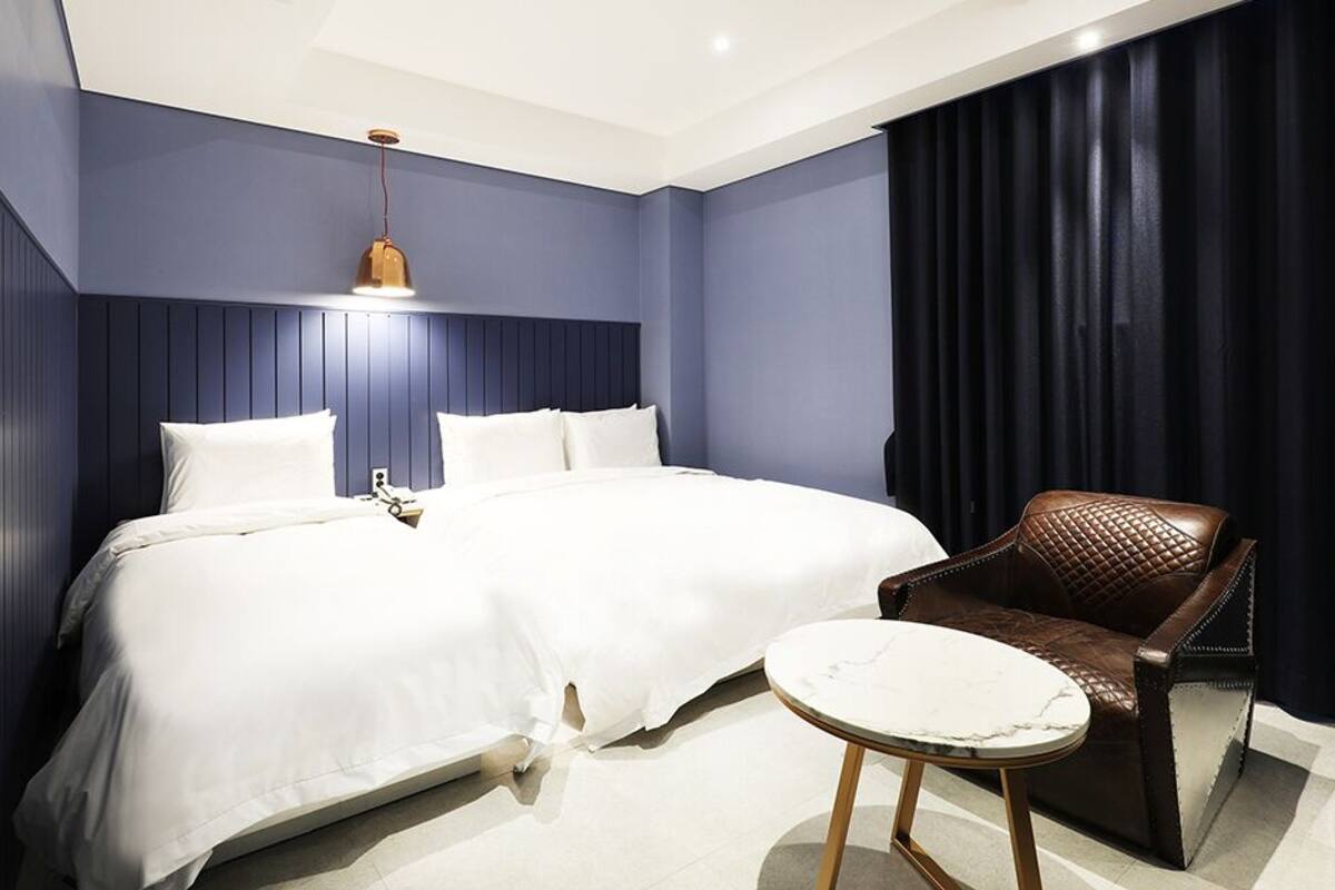 A hotel room with a large bed, a brown leather chair, and a small round table.