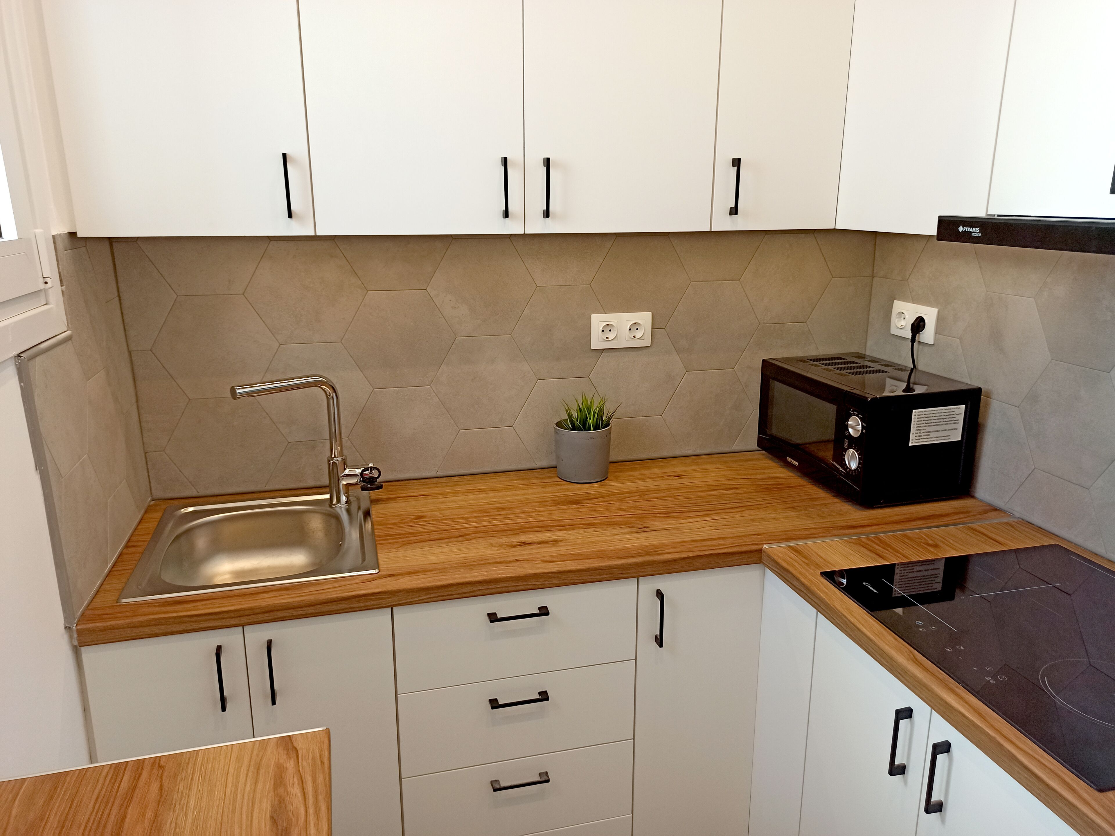 A modern kitchen with white cabinets, a stainless steel sink, a microwave, and a toaster.