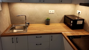 Eine moderne Küche mit Spüle aus Edelstahl, Holz Arbeitsplatte und sechseckigen Fliesen als Rückwand.