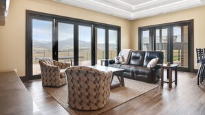 Ein geräumiges Wohnzimmer mit großem Fenster, Deckenventilator und Ledersofa.