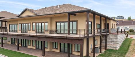 Ein modernes, zweistöckiges Haus mit großen Fenstern, einem Balkon und einer Steinsichtmauer.