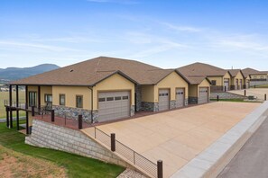 A row of modern houses with garage doors, a stone retaining wall, and a paved driveway. - Spacious w/ Amazing View, Large Deck Spacious Open Plan Near Spearfish (Spearfish)
