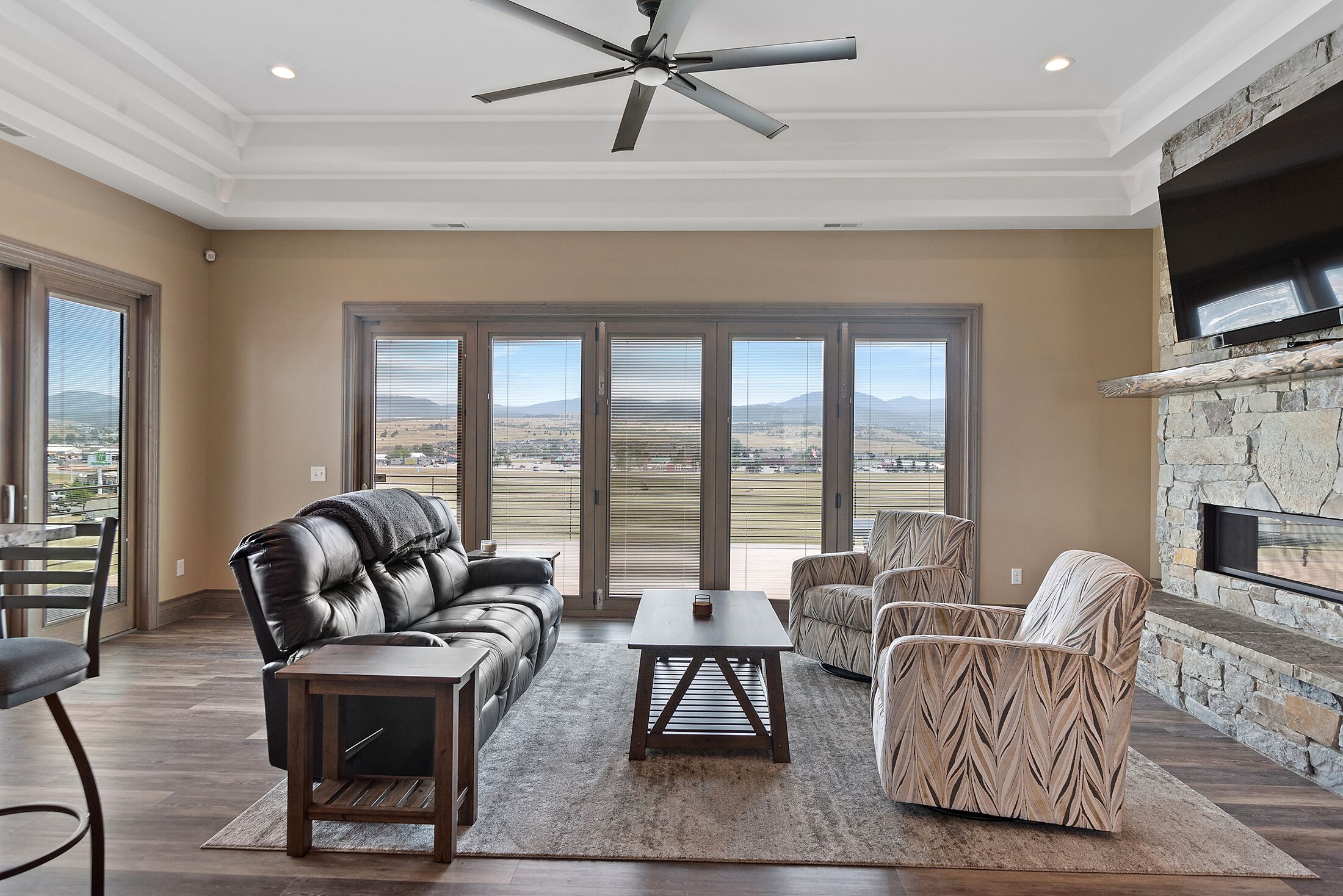 A spacious living room with a leather couch, a wooden coffee table, and a stone fireplace.