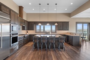 A modern kitchen with a large island, bar stools, stainless steel appliances, and large windows. - Spacious w/ Amazing View, Large Deck Spacious Open Plan Near Spearfish (Spearfish)