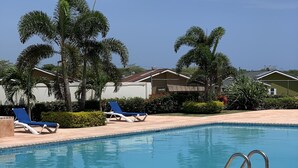 A swimming pool with two blue lounge chairs and a tiled deck. - Luxurious Home (Draxhall)
