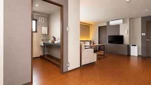 A modern living room with a sofa, a dining table, a TV, and a kitchen area with a sink and cabinets. - The Only View (Osaka)