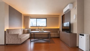 A modern hotel room with a sofa, a small table, a TV, and an air conditioning unit. - The Only View (Osaka)