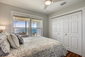 Une chambre avec un grand lit, une porte-fenêtre coulissante donnant sur un balcon et un placard blanc.