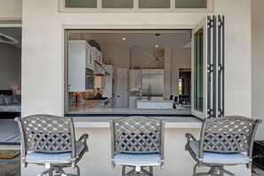 A modern kitchen with white cabinets, stainless steel appliances, and a large window.