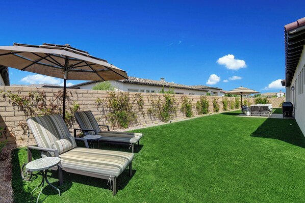 A backyard with a well-maintained lawn, outdoor furniture, and a brick wall.