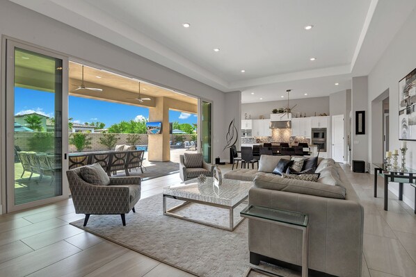 A spacious living area with a large sofa, a coffee table, and a dining set.