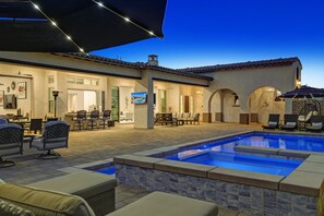 A pool area with lounge chairs and a dining area with tables and chairs.