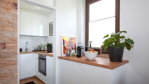 A modern kitchen with white cabinets, a wooden countertop, a built-in oven, and a window with a view. - Glücks-Quartier "Waldhufe 1" (Bad Liebenzell)