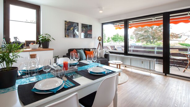 A dining area with a table set for four, a sofa, and a view of the outdoors. - Glücks-Quartier "Waldhufe 1" (Bad Liebenzell)